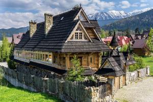 Una gran casa de madera está detrás de una valla en Willa Rajka en Zakopane