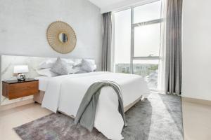 a white bedroom with a large bed and a window at Live and experience an island life - 2BR Apartment in Ras al Khaimah