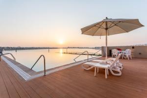 una terrazza con ombrellone, sedie e piscina di Live and experience an island life - 2BR Apartment a Ras al Khaimah