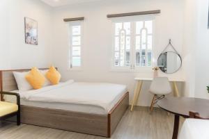 a bedroom with a bed with yellow pillows and a table at Zuchi's Home&Apartment in Da Nang