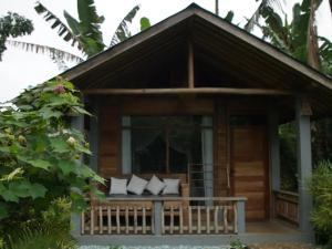 una casa con porche con almohadas blancas en The Geckos Homestay, en Kelimutu