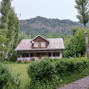 a house with a tin roof on a field at PK cottage in Pahalgām