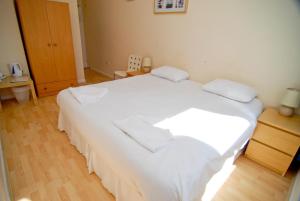 a large white bed in a room with a wooden floor at The Aqua in Portland