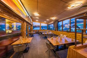 restauracja z drewnianymi stołami i krzesłami oraz oknami w obiekcie Wellness- und Familienhotel Dachsteinresort w mieście Rußbach am Paß Gschütt