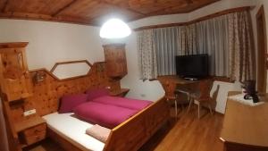 a bedroom with a bed and a desk and a television at virgen-urlaub in Virgen