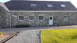 a stone house with a white door and windows at Bodrual cottage in Caernarfon