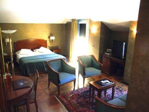 a hotel room with a bed and chairs and a table at Hotel Palazzo Lovera in Cuneo