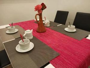 una mesa con platos y tazas y un jarrón con una rosa en En el centro histórico, con el encanto de Portales, en Logroño