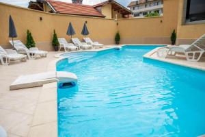 a swimming pool with white chairs and chairs in a building at Хотел Дани in Sandanski
