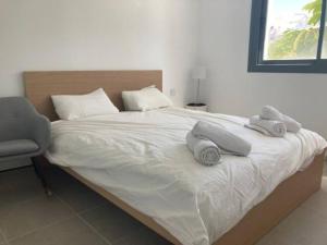 a bed with two towels on it with a chair at Appartement Casares - Mer, Golf, Piscine, Padel - FINCA CORTESIN in Estepona