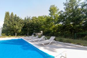 a row of lounge chairs next to a swimming pool at Villa Mela in Sarajevo