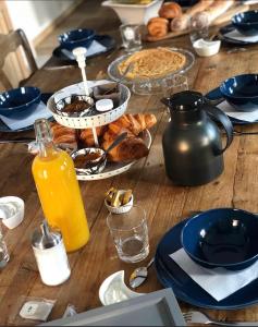 a wooden table with breakfast foods and orange juice at Les Chambres d'hotes de Sophie in Piennes