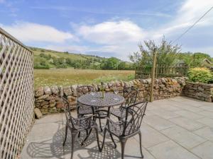 a table and chairs on a patio with a stone wall at Grace Cottage in Bishop Auckland