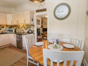 a kitchen and dining room with a table and a clock on the wall at Grace Cottage in Bishop Auckland