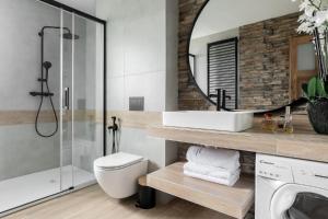 La salle de bains est pourvue d'un lavabo, de toilettes et d'un miroir. dans l'établissement Apart-Center Motola Residence, à Zakopane