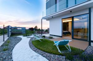 una casa con dos sillas de jardín en el patio delantero en Przystań Mechelinki- Marina Del Mar en Mechelinki