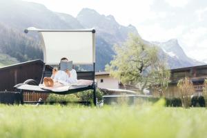 un par de personas tumbadas en una silla en un campo en Hotel Garni Romantika, en Sankt Leonhard im Pitztal