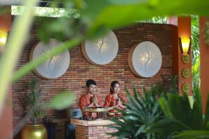 
two people standing in front of a brick wall at Villa Indochine D'angkor in Siem Reap
