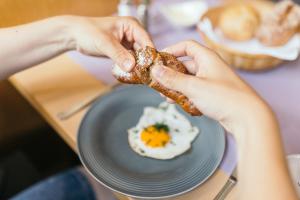a person eating a fried egg on a plate at Hotel Garni Romantika in Sankt Leonhard im Pitztal