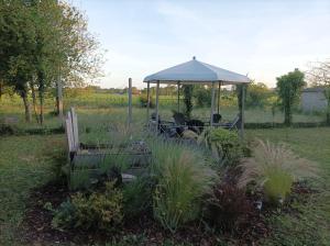 a gazebo with two benches in a garden at charmant studio 35m² au calme proche du circuit in Saint-Gervais en-Belin