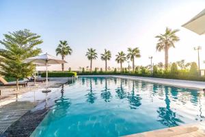 a pool with palm trees and an umbrella at Smart Living Villa in Dubai