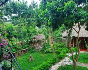 un jardín con una cabaña y un patio con césped en Ninh Binh Bamboo Farmstay, en Ninh Binh