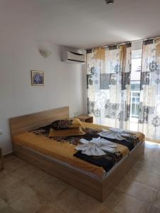 a large bed in a bedroom with a large window at Къща за гости WEST in Sunny Beach
