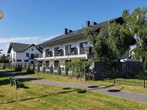 a white building with a fence in front of it at Apartamenty Łuska Rowy in Rowy