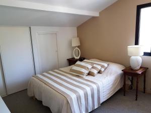 a bedroom with a bed with striped sheets and pillows at Ref 111 Seignosse, Villa de standing 4 étoiles partiellement climatisée avec piscine chauffée et Wifi au calme sur terrain 1100m2 in Seignosse