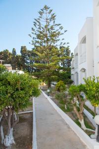 einen Gehweg in einem Park mit Bäumen und einem Gebäude in der Unterkunft Irene Hotel Leros in Alinda