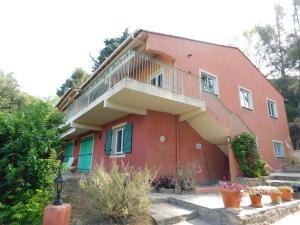 ein rotes Haus mit einem Balkon und einigen Pflanzen in der Unterkunft Villa 54 - Plage Aiguebelle 250m in Le Lavandou