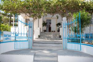 Irene Hotel Leros في أليندا: مدخل الى بيت ابيض بالبوابات الزرقاء