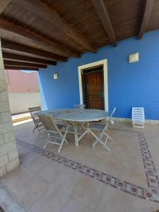 une table et des chaises sur une terrasse avec un mur bleu dans l'établissement Villa Serena, à Granelli