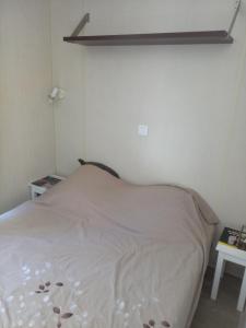 een kleine slaapkamer met een wit bed en een plank bij MOBIL HOME 3 Chambres Climatisé au CAMPING DES ISCLES in La Roque-dʼAnthéron