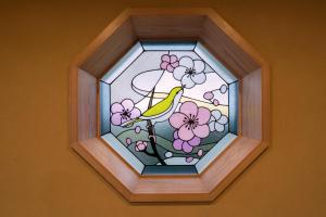 京都的住宿－Kyoto Umekoji Kadensho，鸟坐在鲜花枝上的彩色玻璃窗