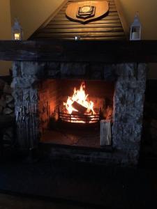 a brick fireplace with a fire in it at Aherlow House Hotel & Lodges in Aherlow