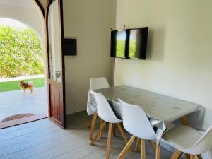 une salle à manger avec une table et des chaises blanches dans l'établissement Villino Oleandro a pochi passi dalla spiaggia di Simius, à Simius