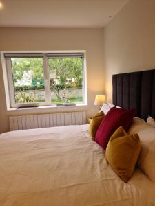Ard Kielin Apartment Luxury 2 bedroom in Killarney في كيلارني: غرفة نوم بسرير كبير ومخدات صفراء وحمراء