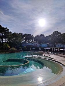 una piscina con gente en el agua en Maisonnette mitoyenne 2 étoiles paisible piscine océan lac vélo marche idéal pour tous en Lacanau-Océan