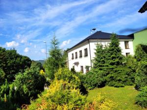 un edificio blanco con árboles delante de él en Apartmánový Dům Pasťák en Loučná nad Desnou