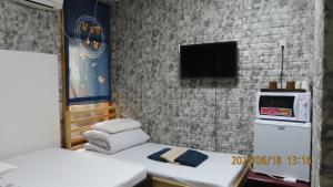a room with two beds and a tv on a brick wall at Sophiearth Apartment in Tokyo
