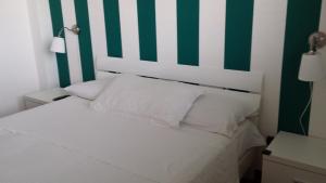 uma cama com uma parede com riscas verdes e brancas em Marinagri Policoro em Policoro