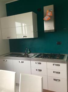 uma cozinha com armários brancos, um lavatório e uma parede verde em Marinagri Policoro em Policoro