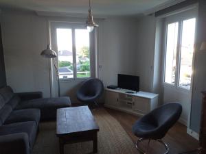 a living room with a couch and two chairs and a television at La petite histoire in Brive-la-Gaillarde