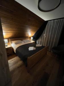 a bedroom with a large bed with a wooden wall at View & Spa Villa in Kluszkowce