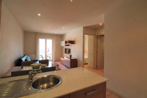 a kitchen with a sink and a living room at Unio Lloret Beach in Lloret de Mar