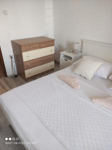 een slaapkamer met een wit bed en een houten dressoir bij Apartmani Lana in Šibenik