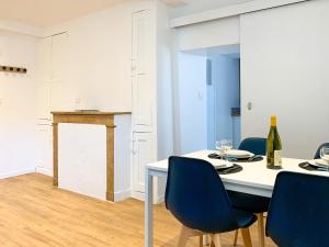 a dining room with a white table and blue chairs at Ambiance Cosy in Buxy