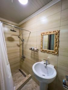 uma casa de banho com um lavatório e um chuveiro com um espelho. em East House em Samarkand