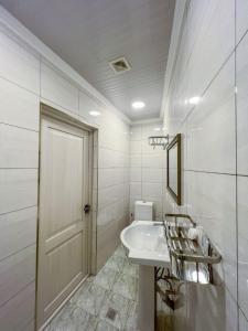 uma casa de banho branca com um lavatório e um espelho em East House em Samarkand
